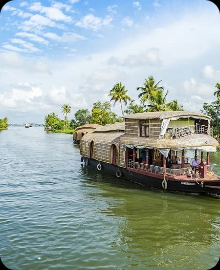 Traditional Kerala houseboat cruising through calm backwater canals lined with coconut palm trees